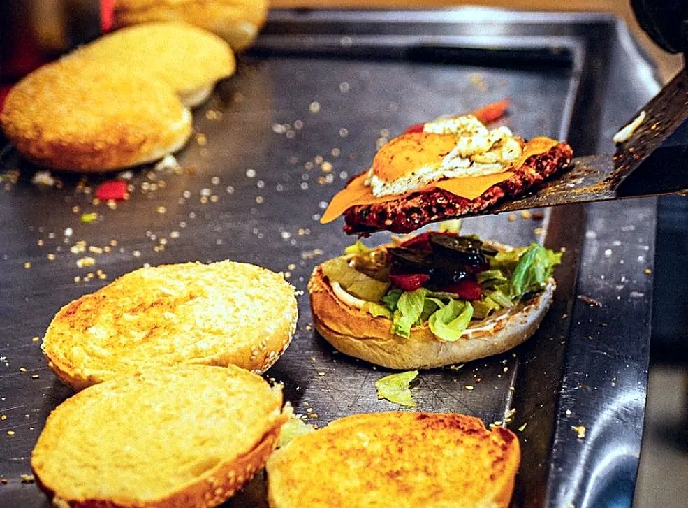 Steak, œuf et cheddar déposés sur un burger à la plancha